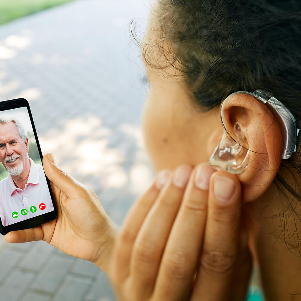 hearing aid in ear, with woman on phone